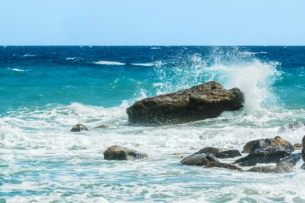 Gematigde zee golven raken de rotsen — Stockfoto