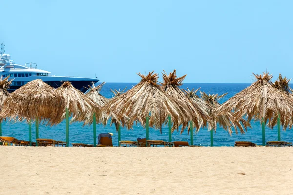 Blauwe zee, gouden zand en ligbedden op het strand — Stockfoto