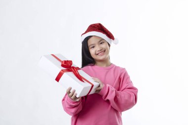Neşeli ve mutlu Asyalı Noel kızı Noel Baba şapkası takıyor hediye kutusunu beyaz bir arka planda izole edilmiş bir şekilde elinde tutuyor.