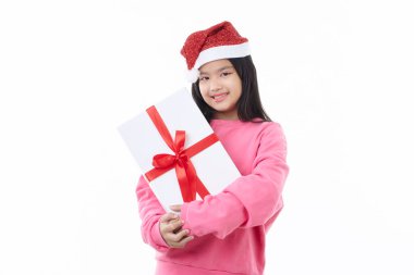 Neşeli ve mutlu Asyalı Noel kızı Noel Baba şapkası takıyor hediye kutusunu beyaz bir arka planda izole edilmiş bir şekilde elinde tutuyor.