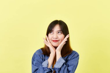 Sarı arka plan güzellik ve yüz ifadeleri üzerinde izole edilmiş kameraya gülümseyen ceketli sevimli, sevimli Asyalı genç kadın esmer.