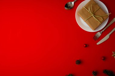 Kırmızı tabaklı Noel masası takımı, kırmızı arkaplan görünümlü şenlikli çatal bıçak takımı.