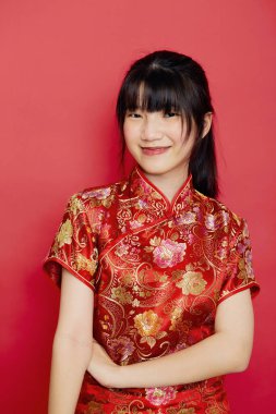 Şirin genç Asyalı kadın Çin 'in yeni yıl konsepti için kırmızı arka planda Cheongsam giyiyor.