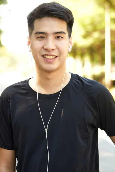 若いですハンサムなアジア人男性運動屋外公園で音楽を聴く — ストック写真