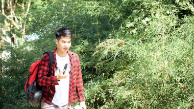 Genç hippi Asyalı bir adam yaz orman gezisi yaşam tarzı konseptiyle sırt çantasıyla seyahat ediyor.