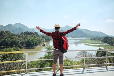 Genç hippi Asyalı bir adam yaz orman gezisi yaşam tarzı konseptiyle sırt çantasıyla seyahat ediyor.