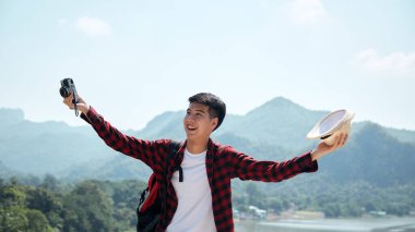 Genç hippi Asyalı bir adam yaz orman gezisi yaşam tarzı konseptiyle sırt çantasıyla seyahat ediyor.