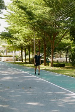 Yakışıklı, genç Asyalı erkek sporcu. Akıllı telefonuyla antrenman müziği dinliyor. Spor kıyafetleri giyiyor, konsept dışında koşuyor.