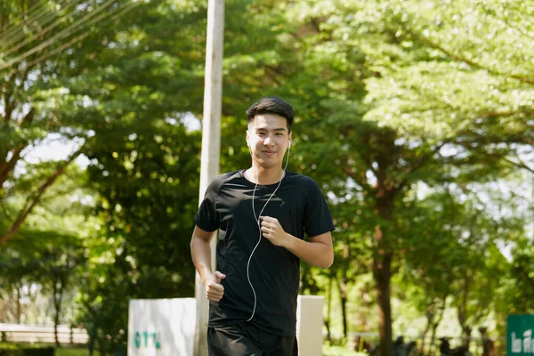 스마트폰에서 음악을 훈련시키는 잘생긴 아시아 선수의 모습은 야외에서 달리는 스포츠 — 스톡 사진
