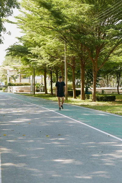 Yakışıklı, genç Asyalı erkek sporcu. Akıllı telefonuyla antrenman müziği dinliyor. Spor kıyafetleri giyiyor, konsept dışında koşuyor.