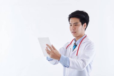 Beyaz önlüklü ve kırmızı steteskoplu dost canlısı bir Asyalı erkek doktor tablet bilgisayar kullanıyor, beyaz arka planda modern tıbbi teknoloji. tıbbi teknoloji kavramı
