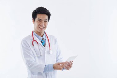Beyaz önlüklü ve kırmızı steteskoplu dost canlısı bir Asyalı erkek doktor tablet bilgisayar kullanıyor, beyaz arka planda modern tıbbi teknoloji. tıbbi teknoloji kavramı