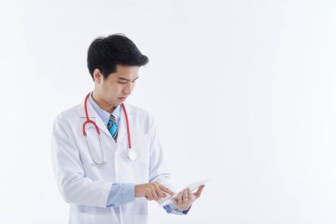 Beyaz önlüklü ve kırmızı steteskoplu dost canlısı bir Asyalı erkek doktor tablet bilgisayar kullanıyor, beyaz arka planda modern tıbbi teknoloji. tıbbi teknoloji kavramı