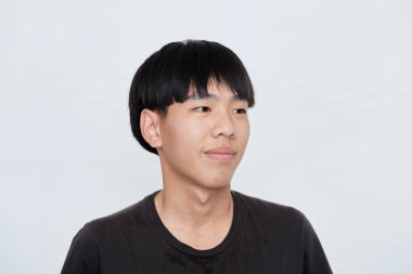 Siyah tişörtlü, gülümseyen Asyalı adam beyaz arka planda izole edilmiş kamera stüdyosuna bakıyor.