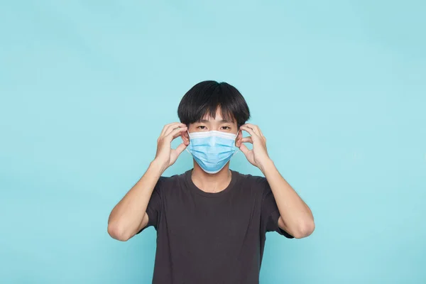 Närbild Ung Asiatisk Man Bär Ansiktsmask Mot Covid Blå Isolerad — Stockfoto