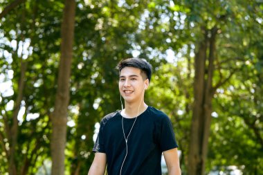 Genç Asyalı mutlu, güler yüzlü bir adam sabah dışarıda koşuyor. Fitness, spor, egzersiz ve egzersiz konsepti..