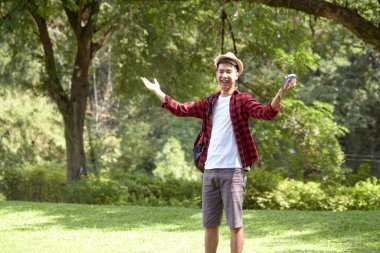 Yeşil ormanda sırt çantası taşıyan yakışıklı ve mutlu bir turist.