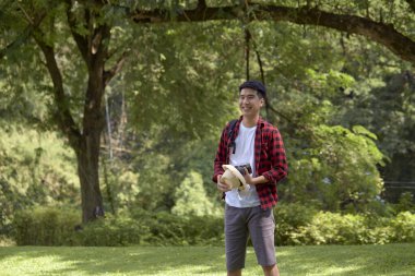 Yeşil ormanda sırt çantası taşıyan yakışıklı ve mutlu bir turist.