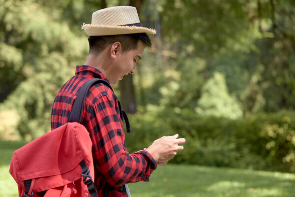 A handsome young Happy tourist man carrying a backpack in the green forest
