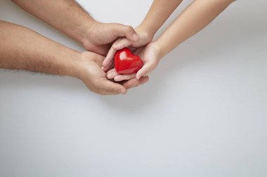 Beyaz arka planda kırmızı kalpli bir adam ve çocuğun elleri