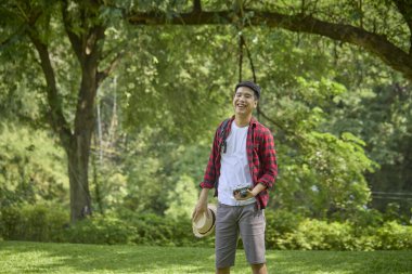 Bir doğa parkında kamerasını tutan genç bir Asyalı sırt çantalı..