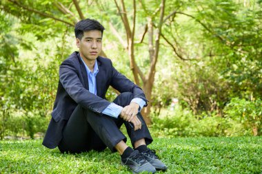 Genç bir Asyalı işadamı doğa parkında dinleniyor.