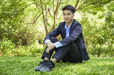 Genç bir Asyalı işadamı doğa parkında dinleniyor.
