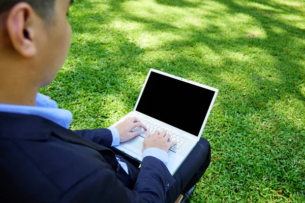 A young Asian businessman sitting in the garden for work