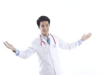 Genç Asyalı doktor beyaz arka planda izole edildi. Tıbbi önlüklü ve steteskop görünümlü erkek doktor sağlık tıbbı konseptini karşılamak için el sallıyor.