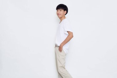 Beyaz arka planda izole edilmiş günlük beyaz tişört stüdyosundaki gülümseyen yakışıklı Asyalı adam.