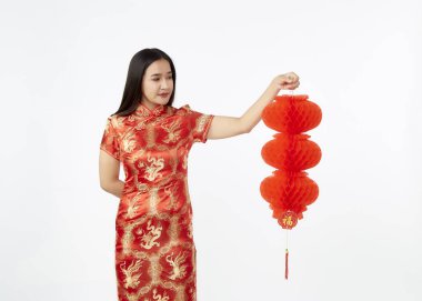 Geleneksel kırmızı Cheongsam elbisesi içindeki genç Asyalı kadın Çin 'e yeni yıl fenerleri tutuyor açık gri izole stüdyo arka planında, Çince karakter servet ve şans demektir.