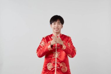 Geleneksel oryantal kostümlü yakışıklı Asyalı adam Çin 'in yeni yıl kavramları için açık gri arka planda izole edilmiş.