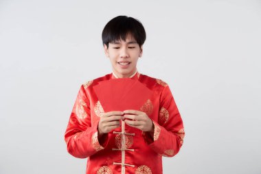 Mandarin yakalı genç bir Asyalı beyaz arka planda kırmızı zarf paketi taşıyor. Çin yeni yıl konsepti.