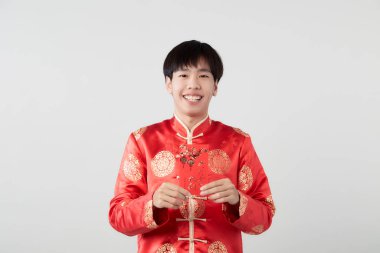 Mandarin yakalı genç bir adam beyaz arka planda kırmızı zarf paketi tutuyor. Çin yeni yıl konsepti.)