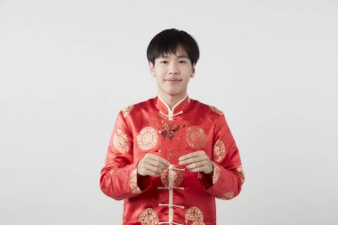 Mandarin yakalı genç bir adam beyaz arka planda kırmızı zarf paketi tutuyor. Çin yeni yıl konsepti.)