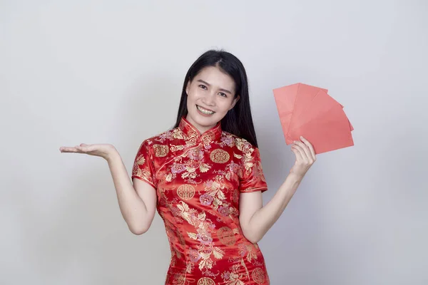 肖像美しい若いアジアの女性は コピースペースと明るい灰色の背景に隔離された幸せな新年の挨拶の赤いパケット金銭の贈り物を保持中国のドレスを身に着けています — ストック写真