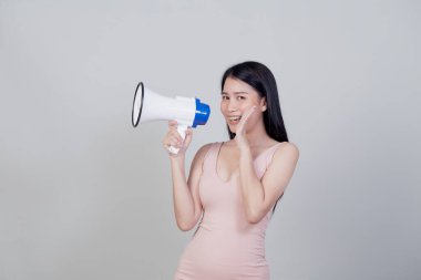 Mutlu güzel Asyalı kadın magafondan konuşuyor açık gri arka planda fotokopi alanı ile izole edilmiş.