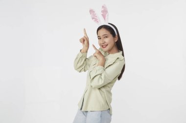 Şenlikli tavşan ve yumurta mevsimi. Paskalya tavşanı kulaklı güzel Asyalı kadın portresi. Beyaz arka planda Paskalya bayramı.