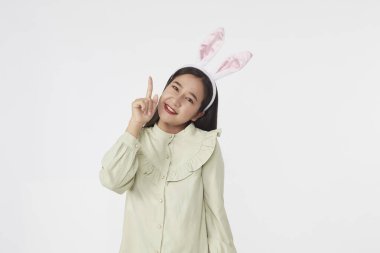 Şenlikli tavşan ve yumurta mevsimi. Paskalya tavşanı kulaklı güzel Asyalı kadın portresi. Beyaz arka planda Paskalya bayramı.