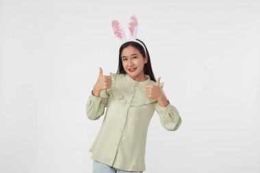 Şenlikli tavşan ve yumurta mevsimi. Paskalya tavşanı kulaklı güzel Asyalı kadın portresi. Beyaz arka planda Paskalya bayramı.