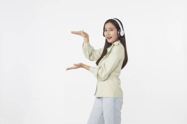 Neşeli, güzel, Asyalı bir kadın dans ediyor, beyaz arka planda kablosuz kulaklıkla müzik dinliyor.