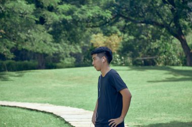 Genç yakışıklı Asyalı spor yapıyor. Üzerinde spor aleti var.