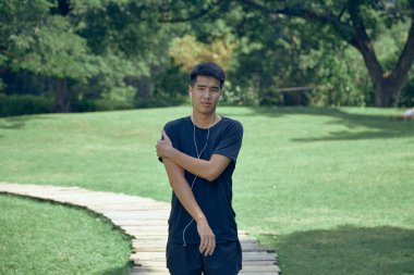 Genç yakışıklı Asyalı spor yapıyor. Üzerinde spor aleti var.