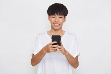 Yakışıklı Asyalı erkek öğrenci arka planda akıllı telefon kullanarak mesajlar yolluyor. Boşluk ve maketi kopyala