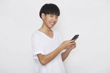 Yakışıklı Asyalı erkek öğrenci arka planda akıllı telefon kullanarak mesajlar yolluyor. Boşluk ve maketi kopyala