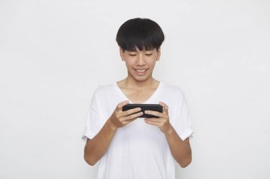 Yakışıklı Asyalı erkek öğrenci arka planda akıllı telefon kullanarak mesajlar yolluyor. Boşluk ve maketi kopyala