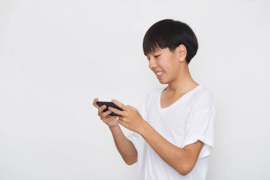 Yakışıklı Asyalı erkek öğrenci arka planda akıllı telefon kullanarak mesajlar yolluyor. Boşluk ve maketi kopyala