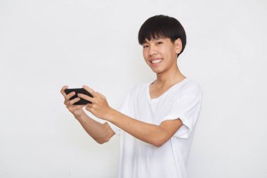 Yakışıklı Asyalı erkek öğrenci arka planda akıllı telefon kullanarak mesajlar yolluyor. Boşluk ve maketi kopyala