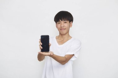 Yakışıklı Asyalı erkek öğrenci arka planda akıllı telefon kullanarak mesajlar yolluyor. Boşluk ve maketi kopyala