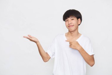 Yakışıklı genç Asyalı bir adam kameraya bakıp gülümserken elini beyaz arka planda gösteriyordu.